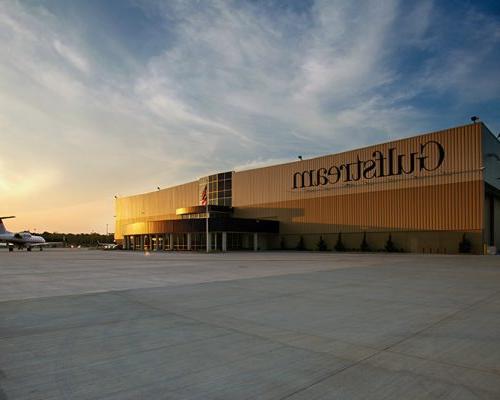 Exterior of Gulfstream Service Center at dusk. Airplane sitting outside of large rectangular building.